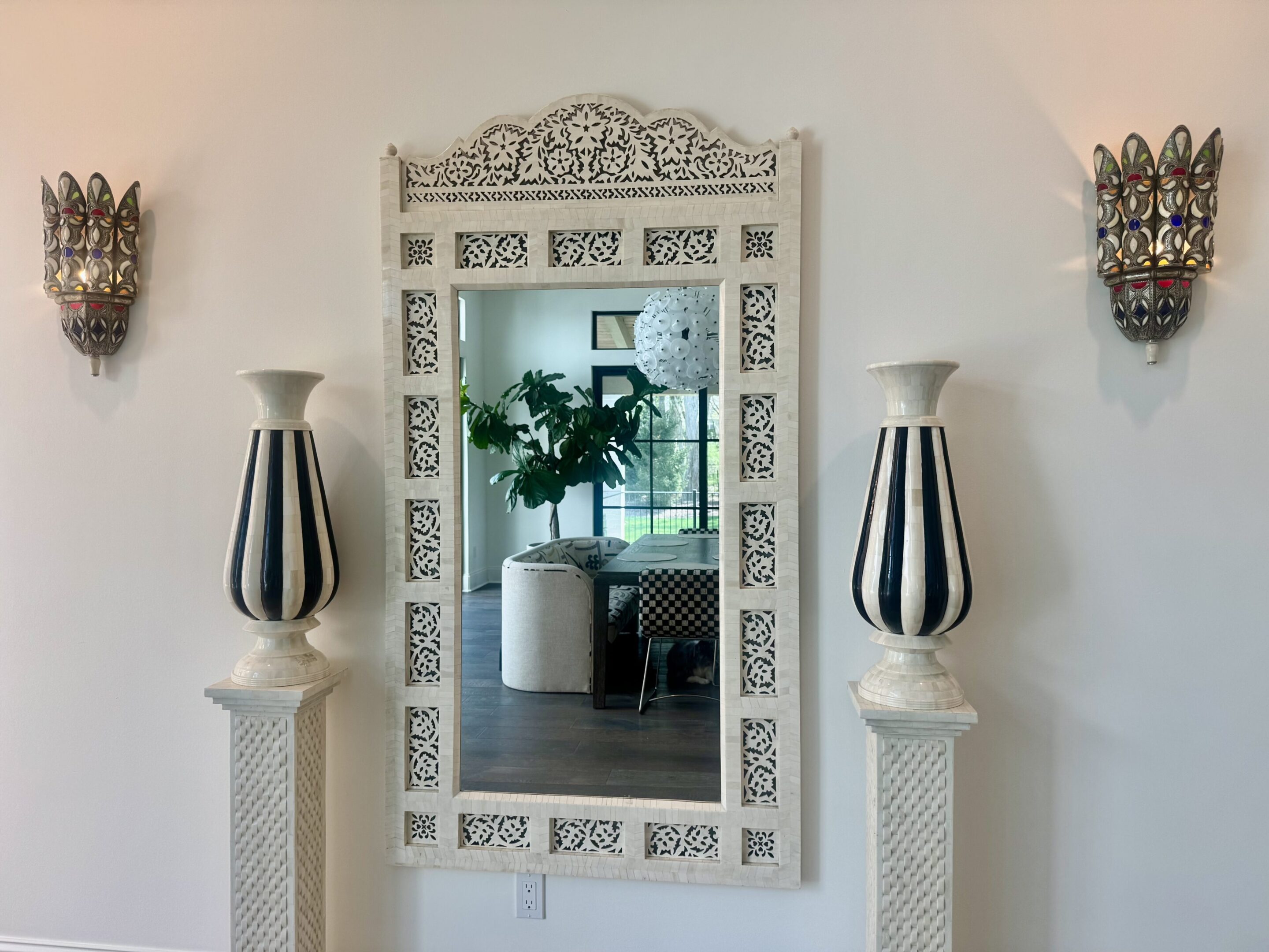 Ornate white mirror flanked by striped vases