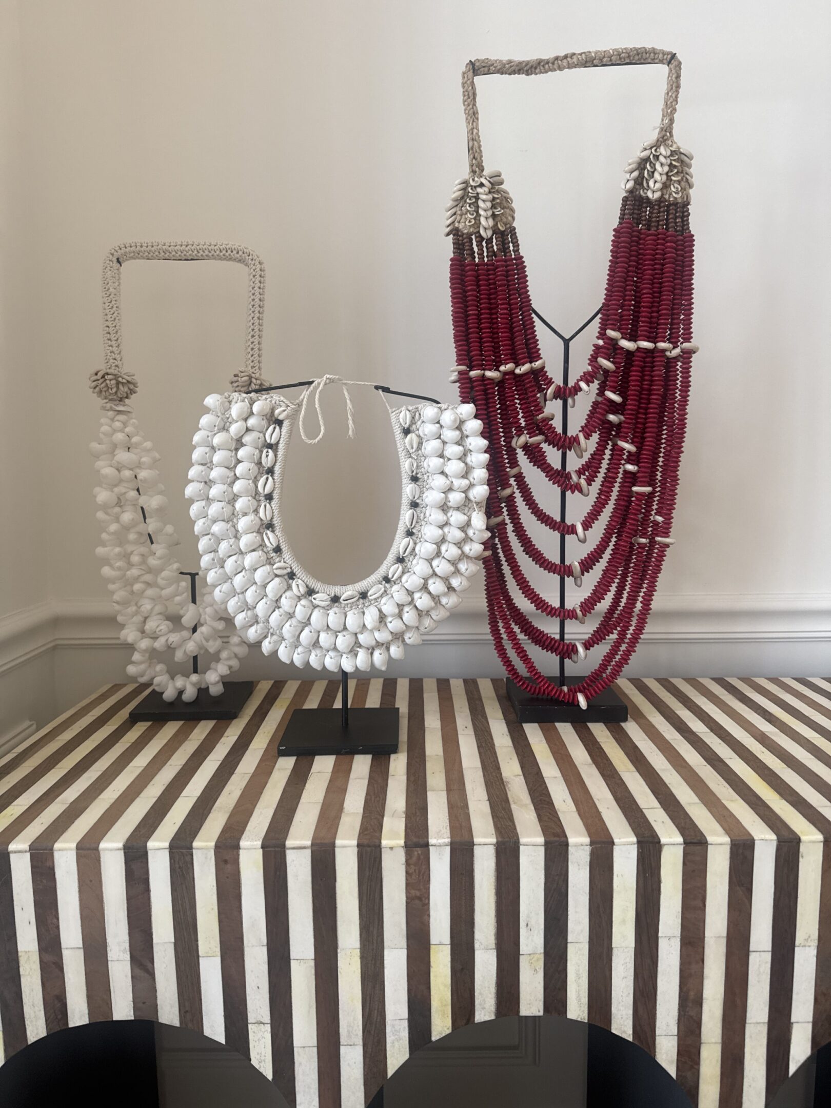 Three statement beaded necklaces displayed on stands